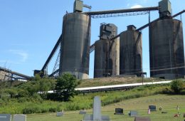 Four silos tower above headstones that sit on a bill below.