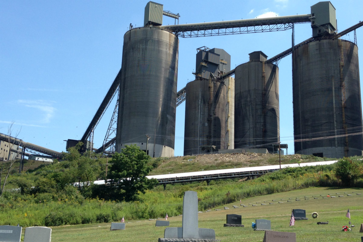 Four silos tower above headstones that sit on a bill below.