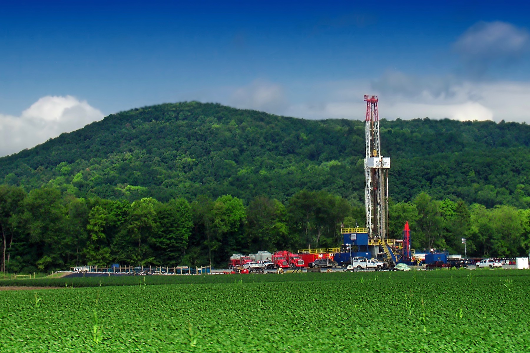 well pad in a green field with hills behind it