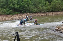 People in a small river on paddle boards