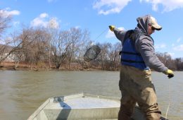 Nevin Welte standing on a small boat in the Allegheny River.