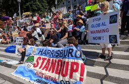 Climate Change Protestors on the steps of the state capitol with a sign that reads," Harrisburg Stand Uo."