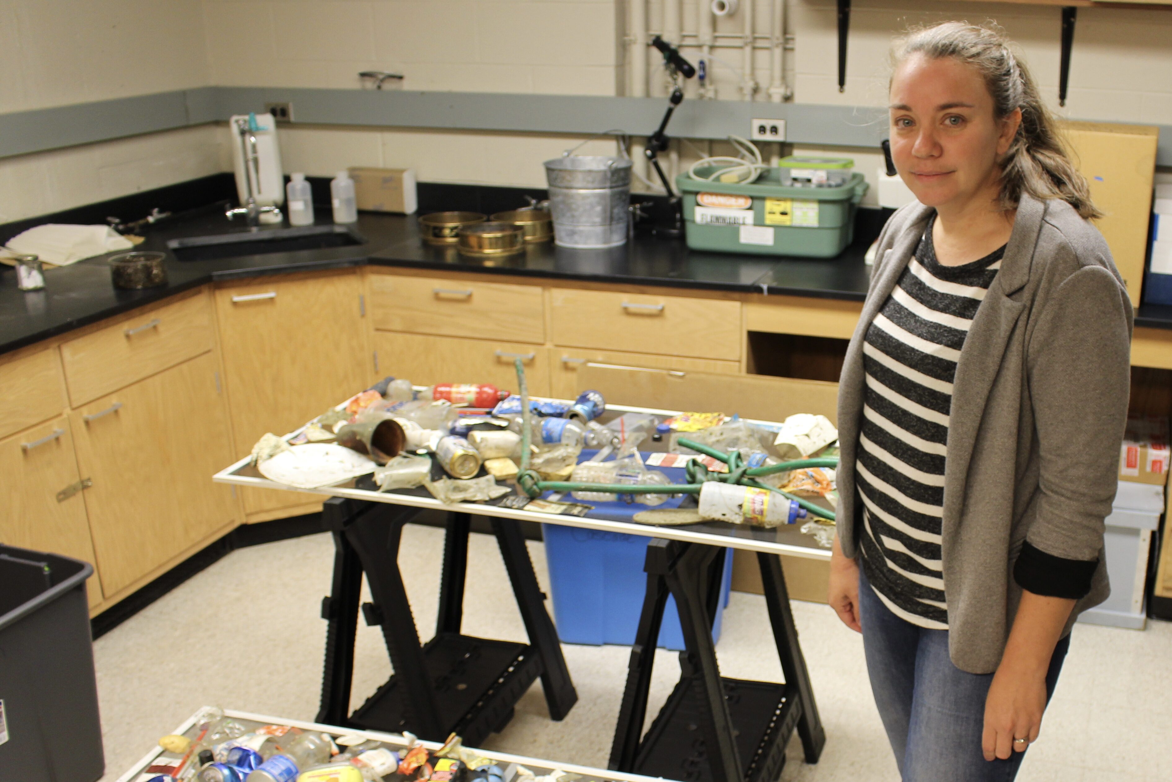 Sherri Mason stands next to tables with plastic trash