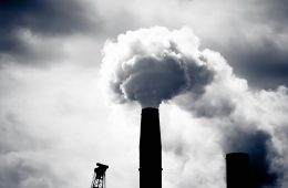 A grey puff of smoke come sout of a dark smokestack