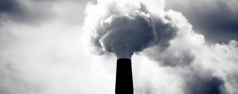 A grey puff of smoke come sout of a dark smokestack