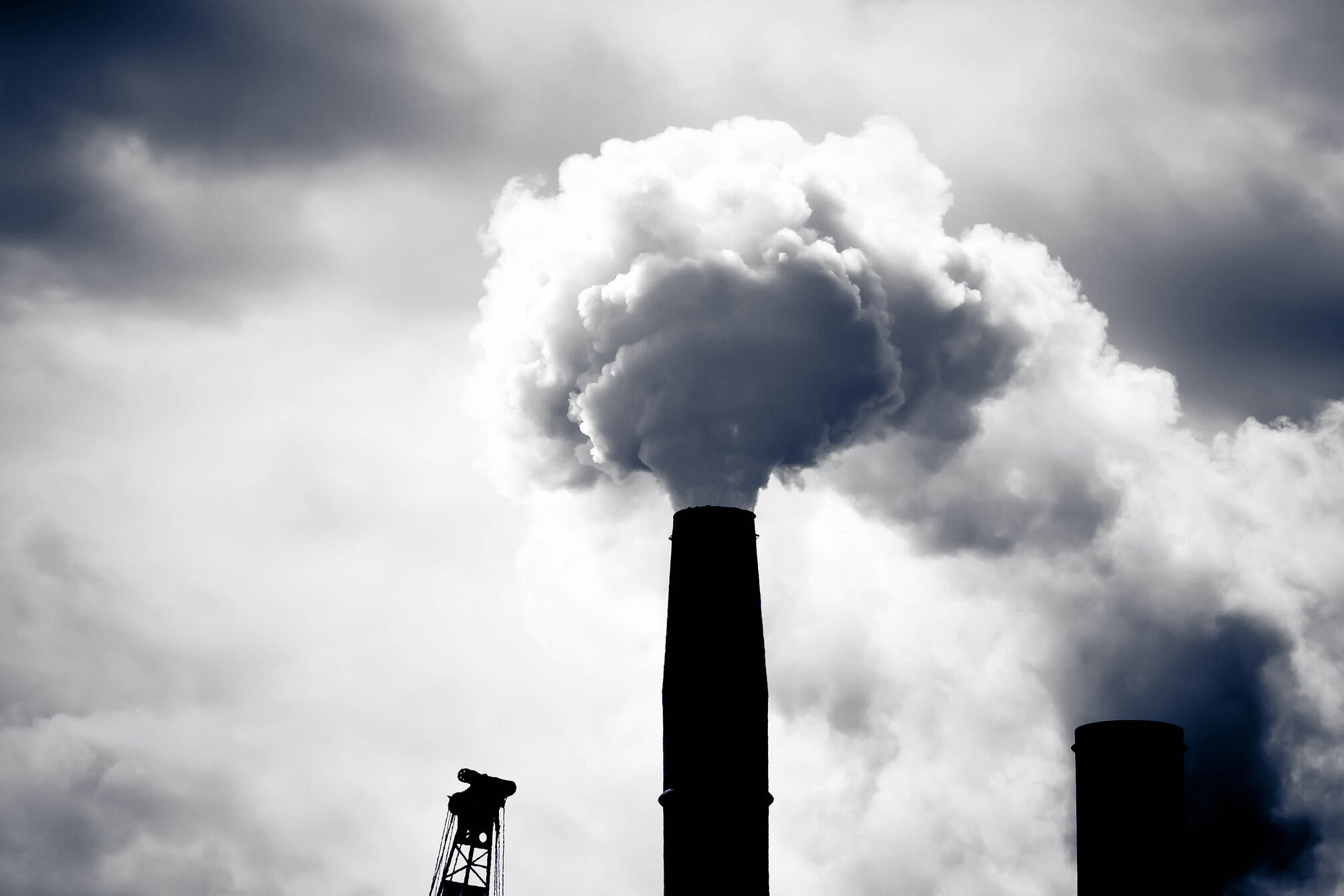 A grey puff of smoke come sout of a dark smokestack