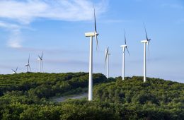 Wind turbines in a row on a green hilltop