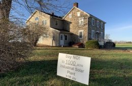 Anti-solar sign in yard with a stone house in the background