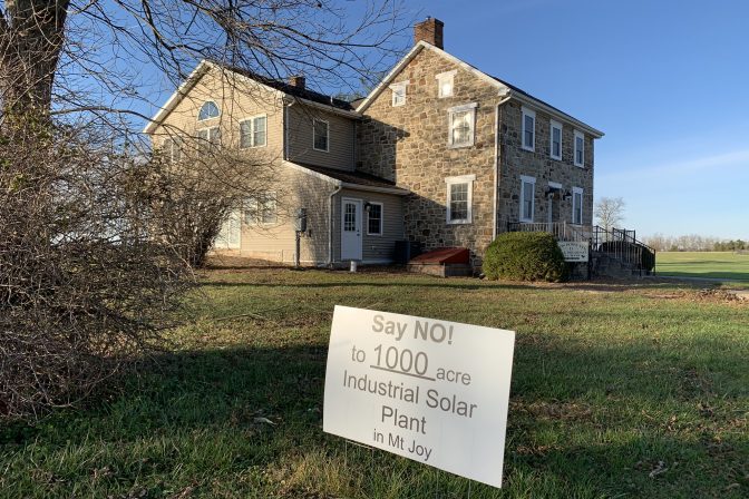 Anti-solar sign in yard with a stone house in the background