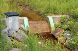 orangish water runs over a small concrete Shute