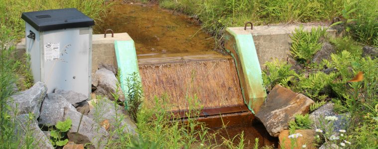 orangish water runs over a small concrete Shute