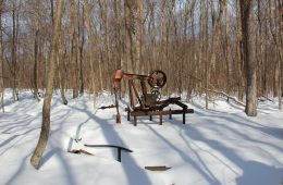 An rusty, abandoned oil well in a snow-covered forest