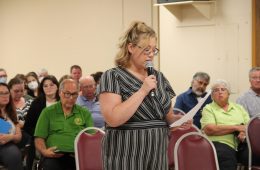 Katie Sheehan talks into a microphone at a public hearing
