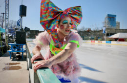 John Jarboe dressed in large colorful bow, on side of the ice rink