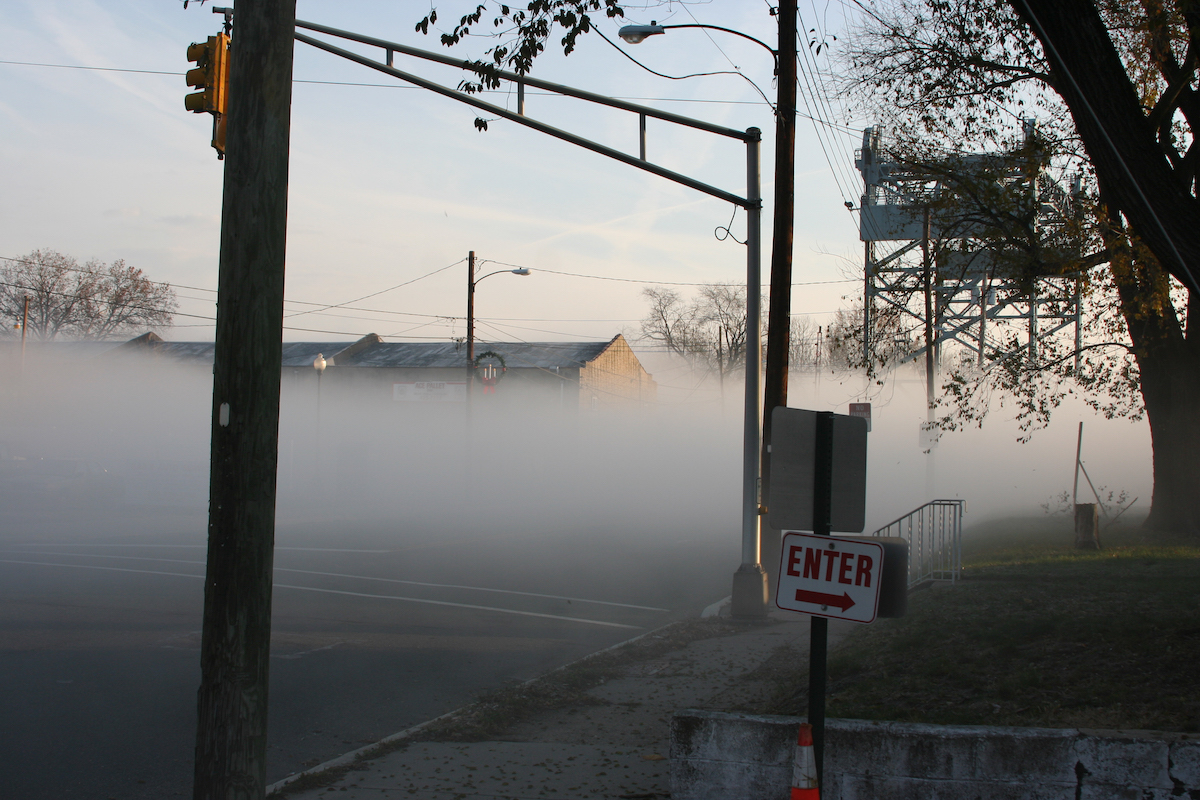 Thick fog-like cloud hovers at ground level on a street.