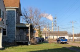 Homes along a street with a smokestack in the background