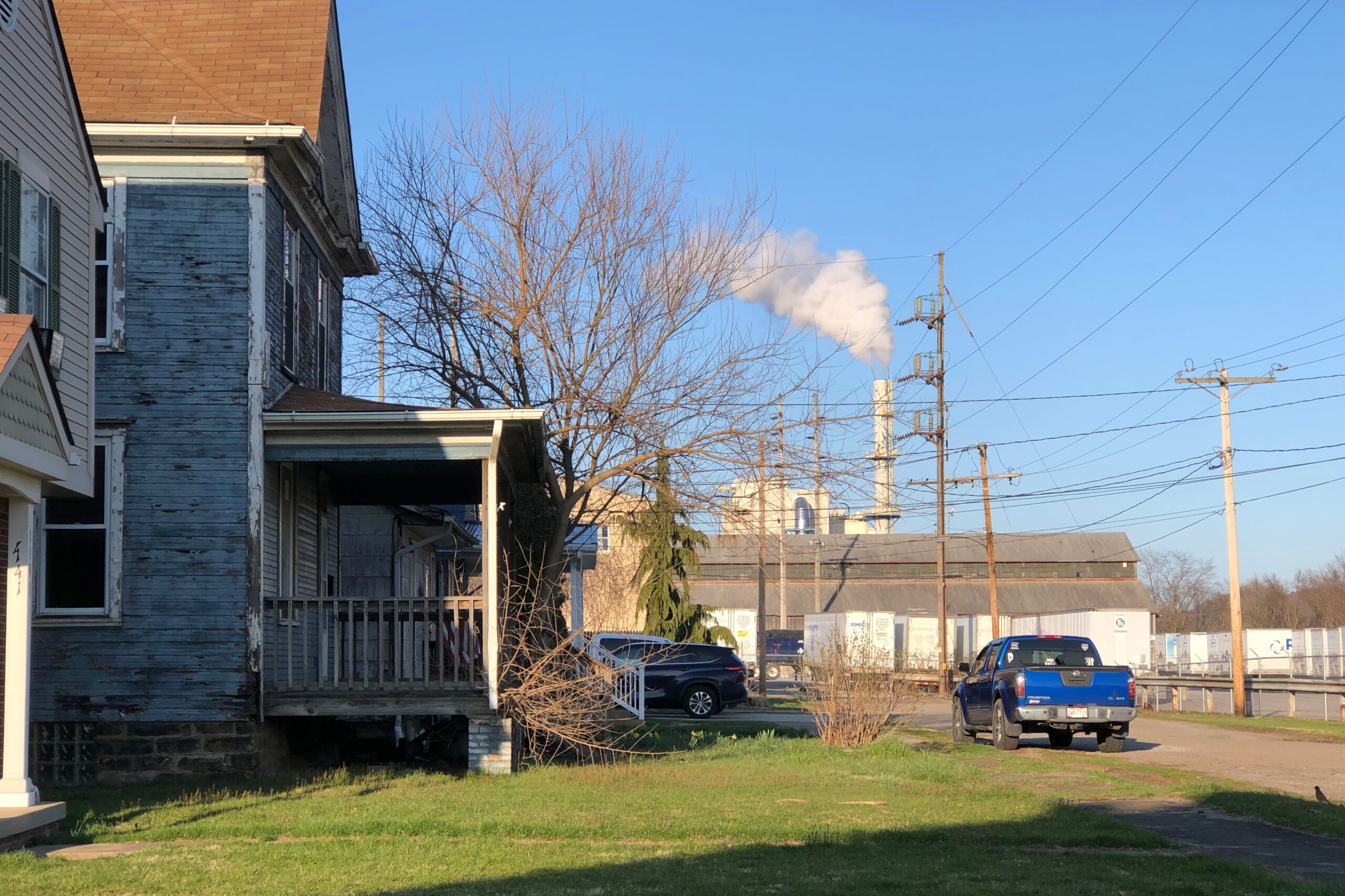 Homes along a street with a smokestack in the background