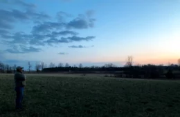 Brian Granger stands at the edge of a field at dusk