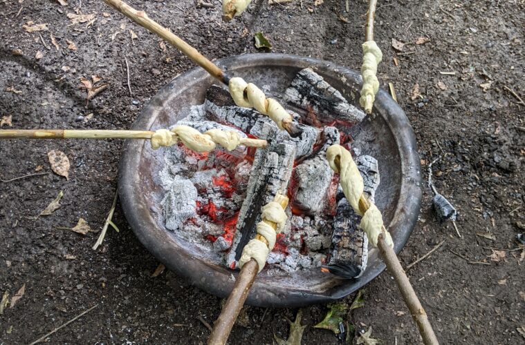 Dough rolled on sticks over a small campfire.