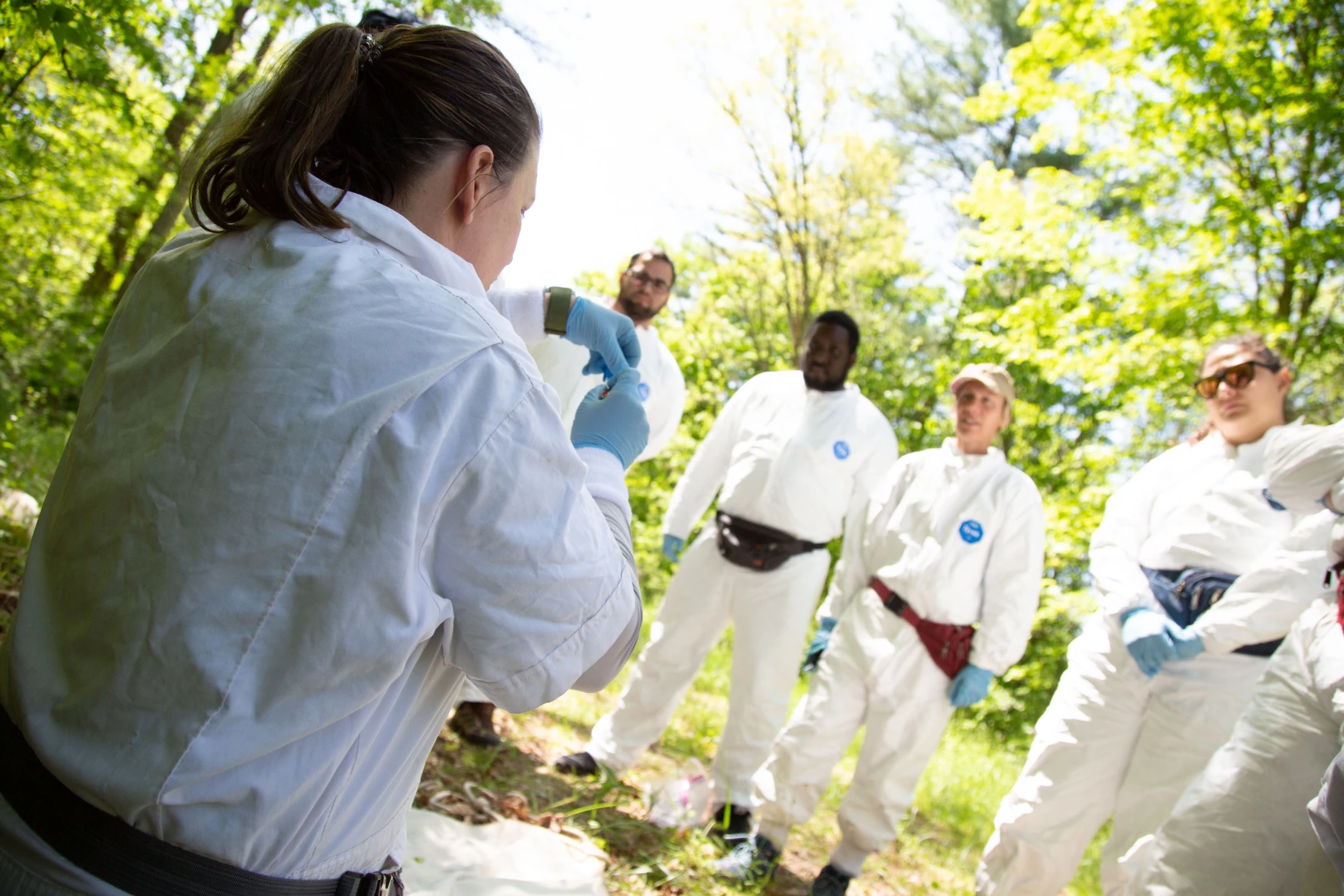 People in white suits standing in a circle outside