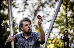 Actor Bob Martin portrays the character of Ezell, standing between two pipes and showin the audience a red hankercheif.