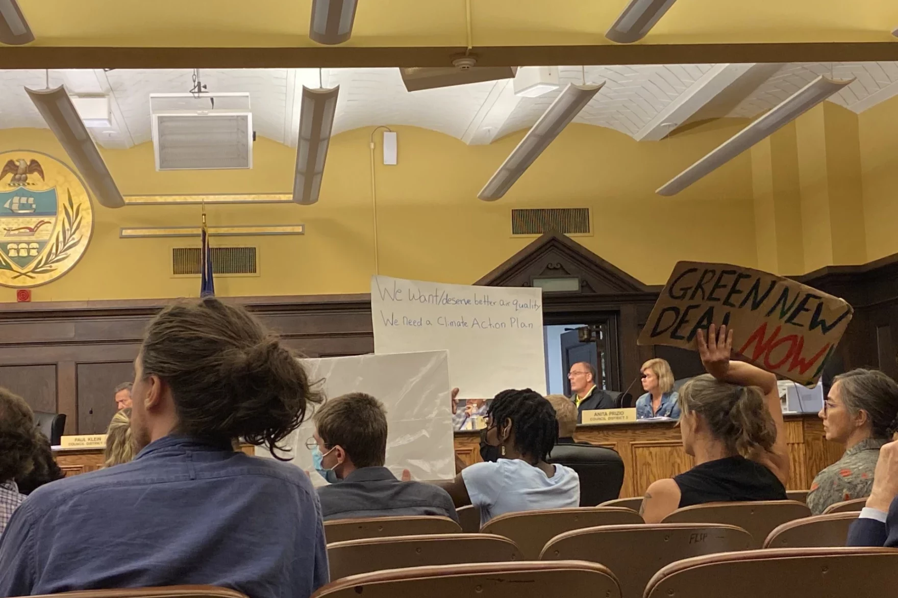 People with signs sitting at the county council meeting.