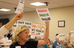 Woman holding a sign that says "SHAME, SHAME, SHAME" among other signs
