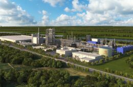 A rendering shows an aerial view of an industrial facility among green fields and trees