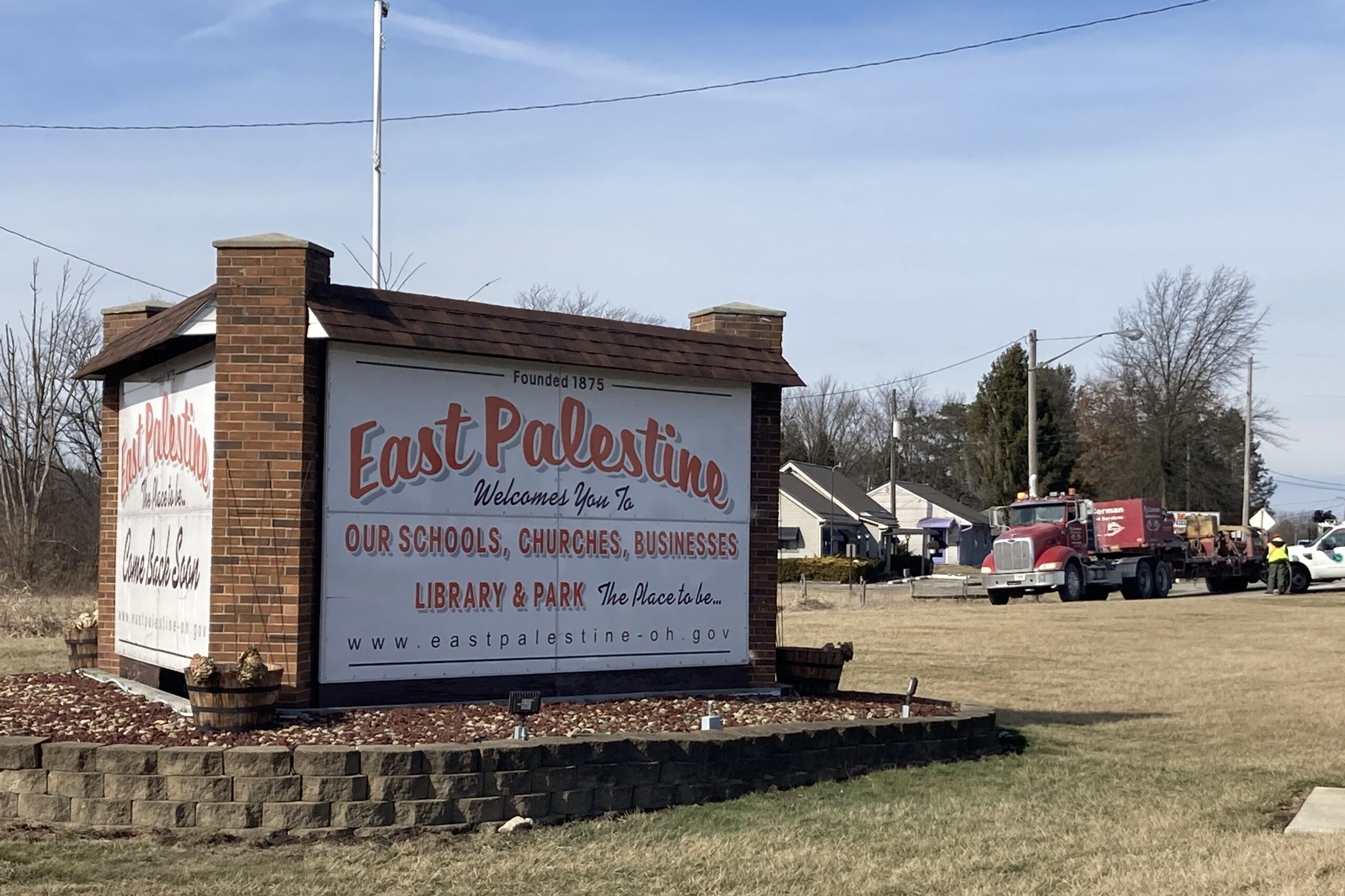 A sign welcoms visitors to East Palestine, Ohio in red lettering.