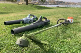 leaf blowers and weed hacker laying in a grassy field