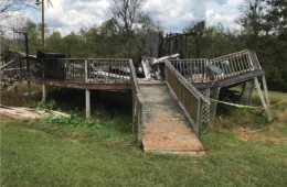 charred remains of a house, with a ramp and deck railing in front