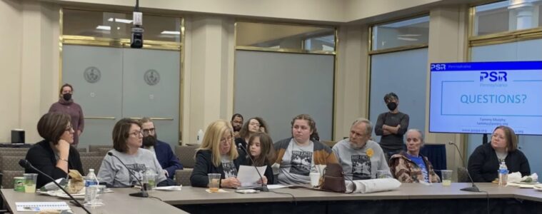 Seven adults and a child sit at an L-shaped conference table