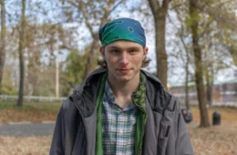 A young man in a green standing bandana outside