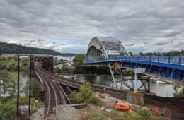 A bridge with railroad bridge next to it crossing a river.