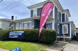 A large 2-story home turned into an office, with a banner outside reading "East Palestine Clnic"