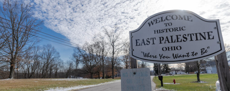 A sign reading "Welcome to East Palestine, Oho, Where you want to be" along a road