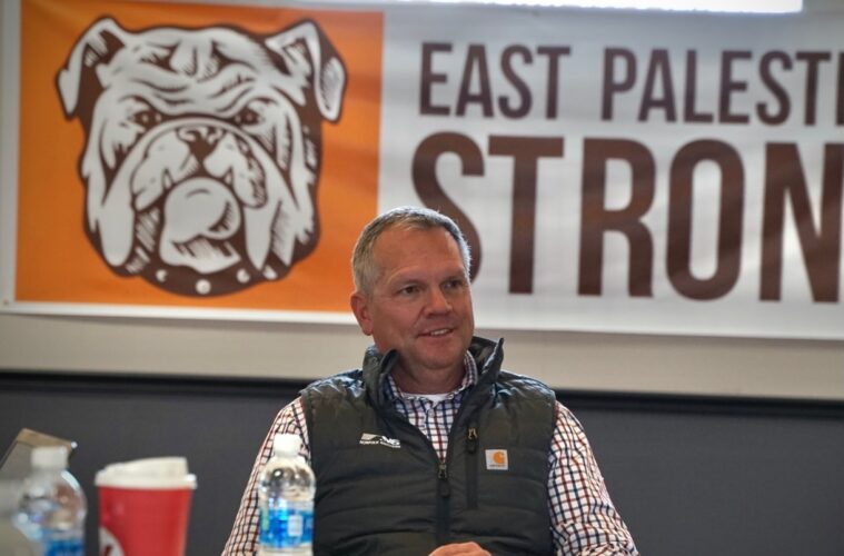 Alan Shaw sits in front of a banner that reads "East Palestine Strong."