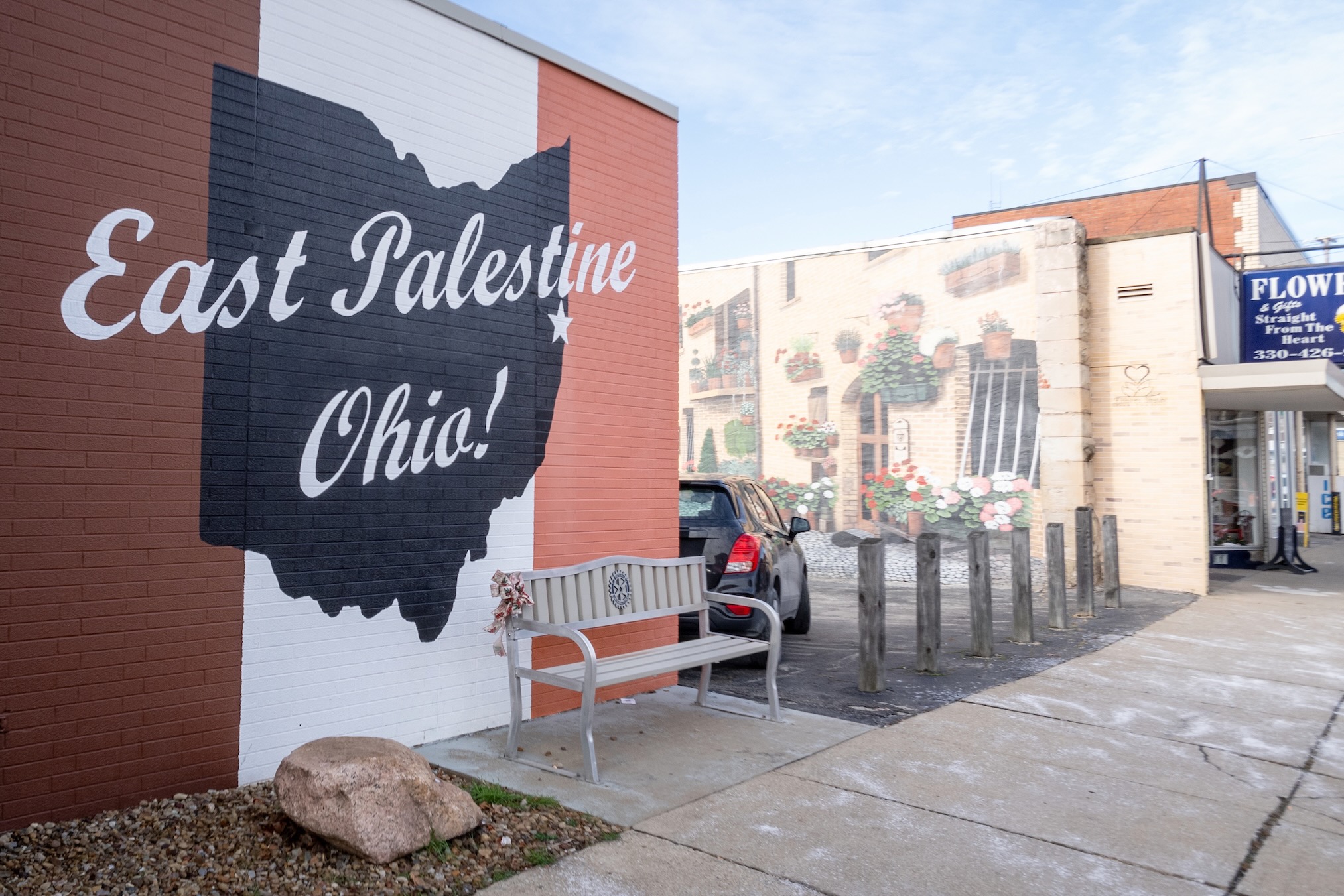 The brick facade of a store is painted with the words "East Palestine, Ohio" in red white and blue.