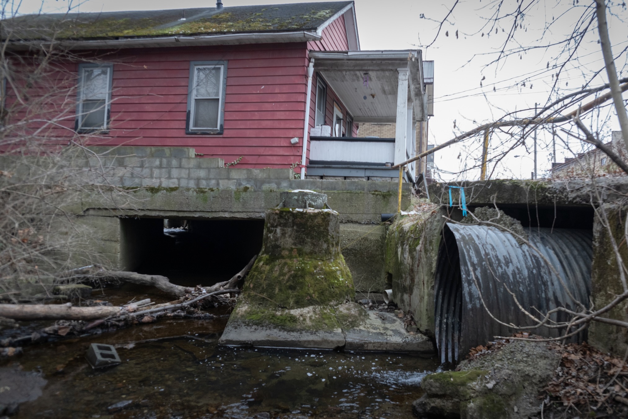 A stream goes under a house through a large culvert