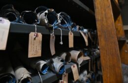 Rolls of maps with hand written tags hanging over shelves.