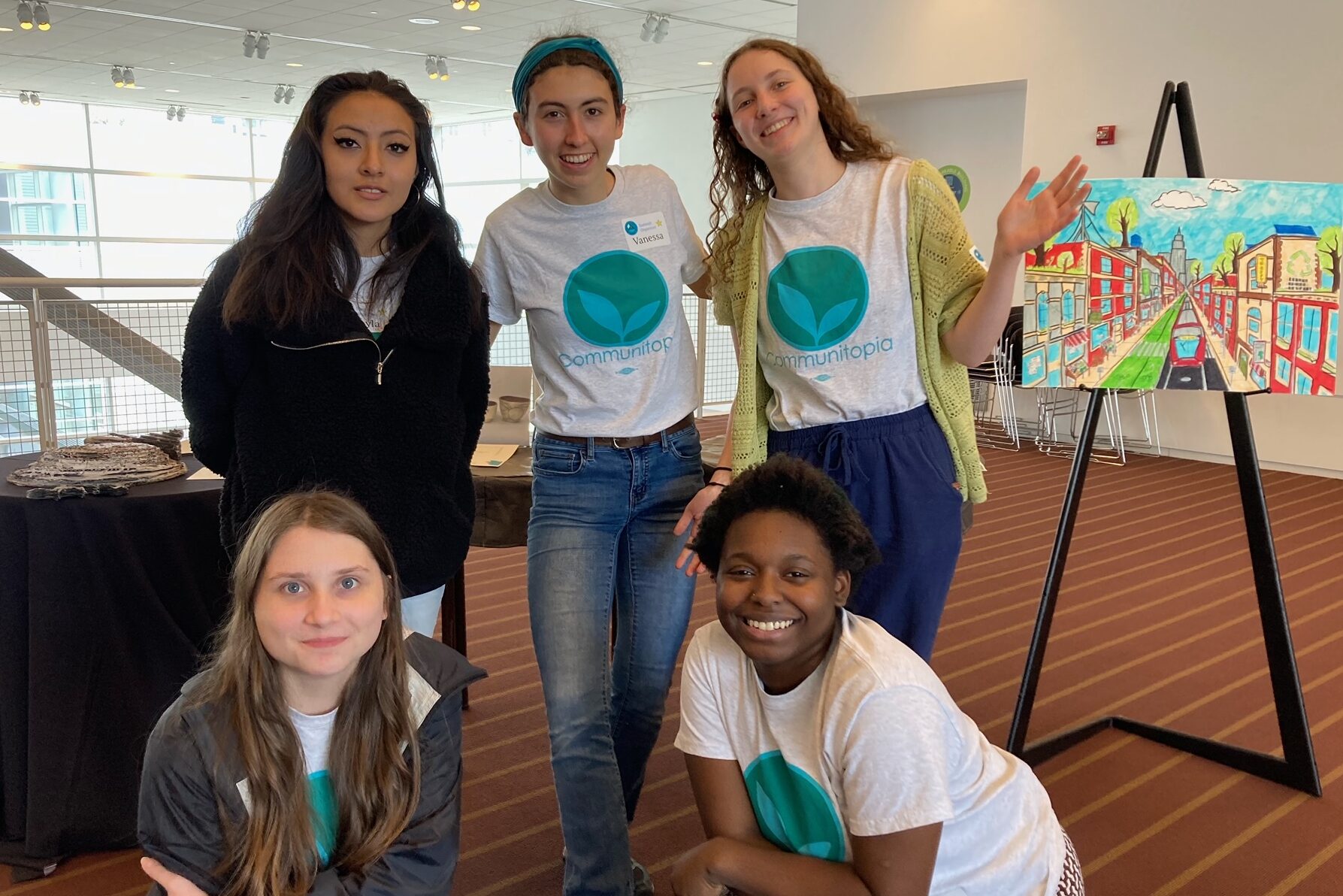Five smiling young people in climate change tee shirts pose together