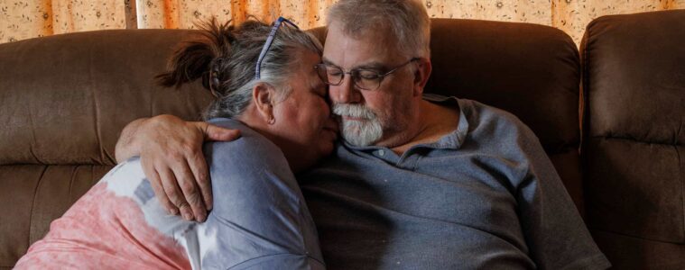 A man and a woman on a couch, embracing.