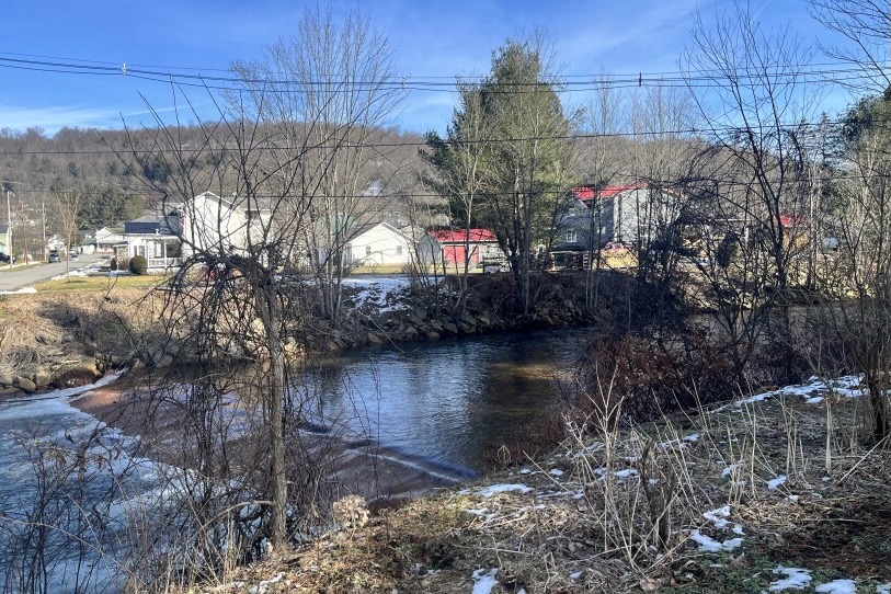 A small river flows next to a tiny hamlet in the winter.