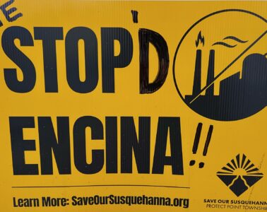 A tellow sign with bold, black lettering against the Encina plant in Point Township.