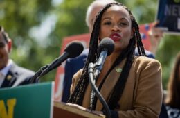 Summer Lee speaks into microphones at a podium outside.