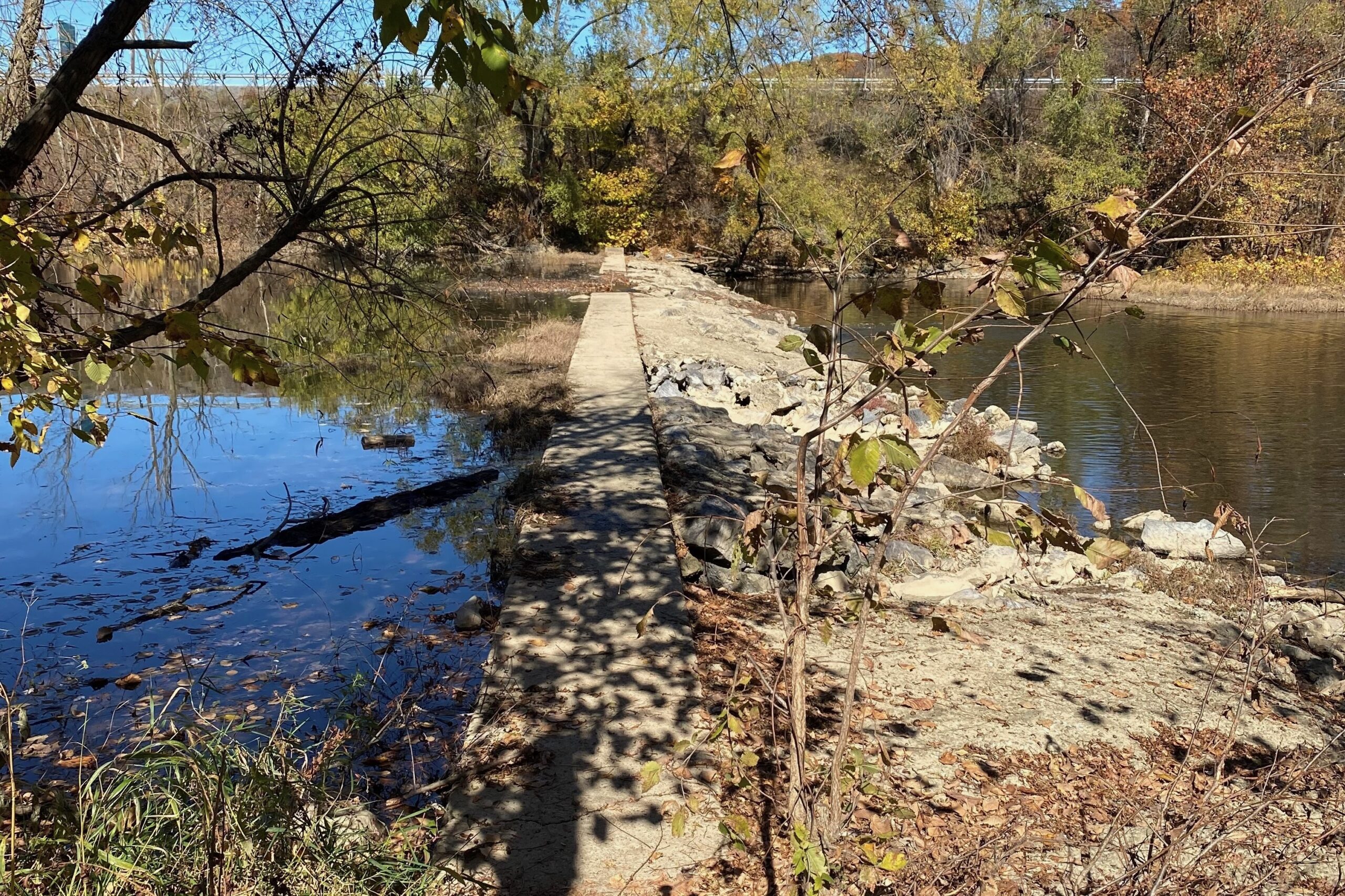 A large concrete barrier runs across a stream