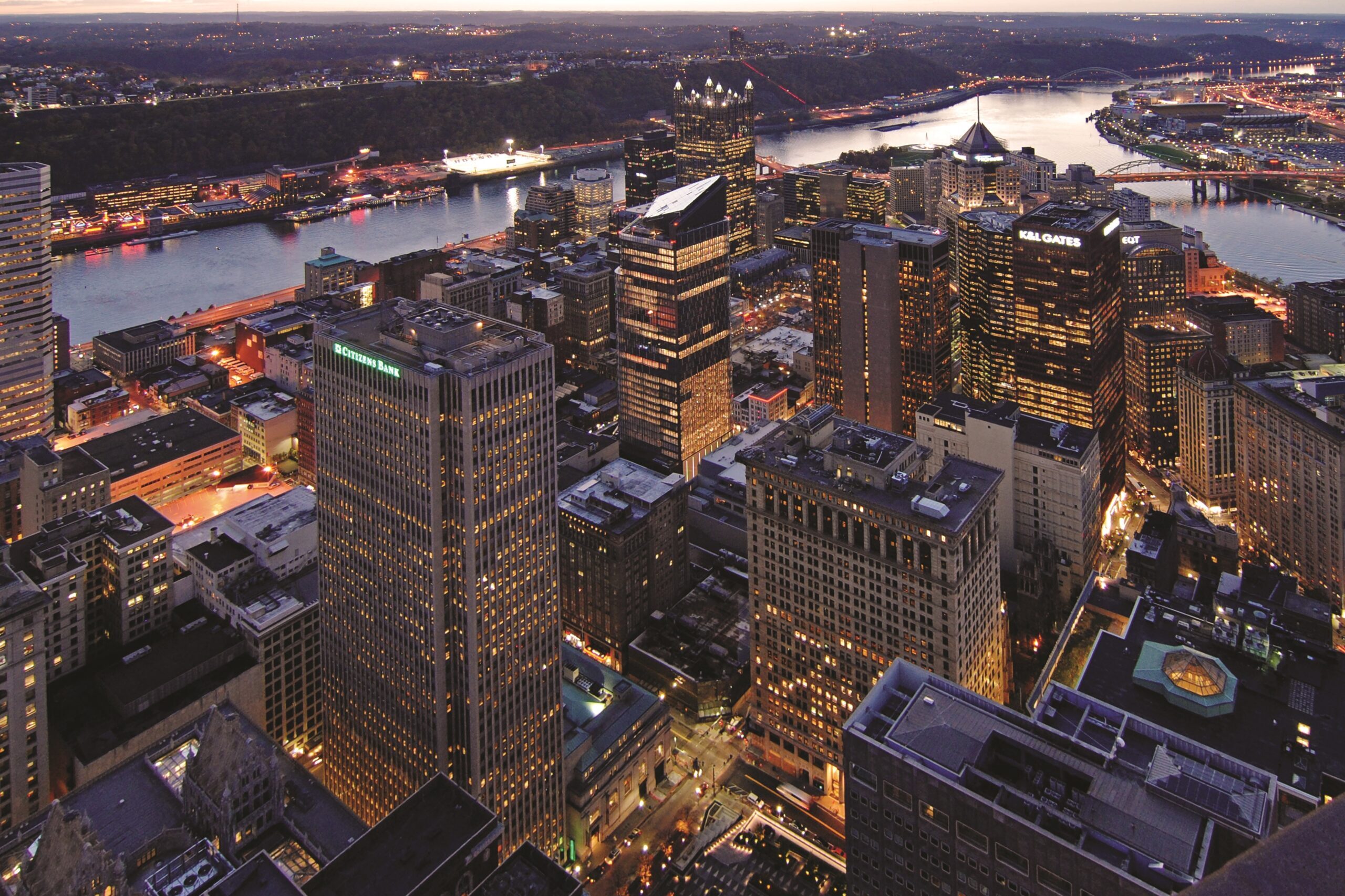 Tall office buildings are lit up against a dark, night sky.