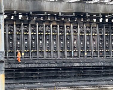 A massive industrial thing with a workers standing next to it