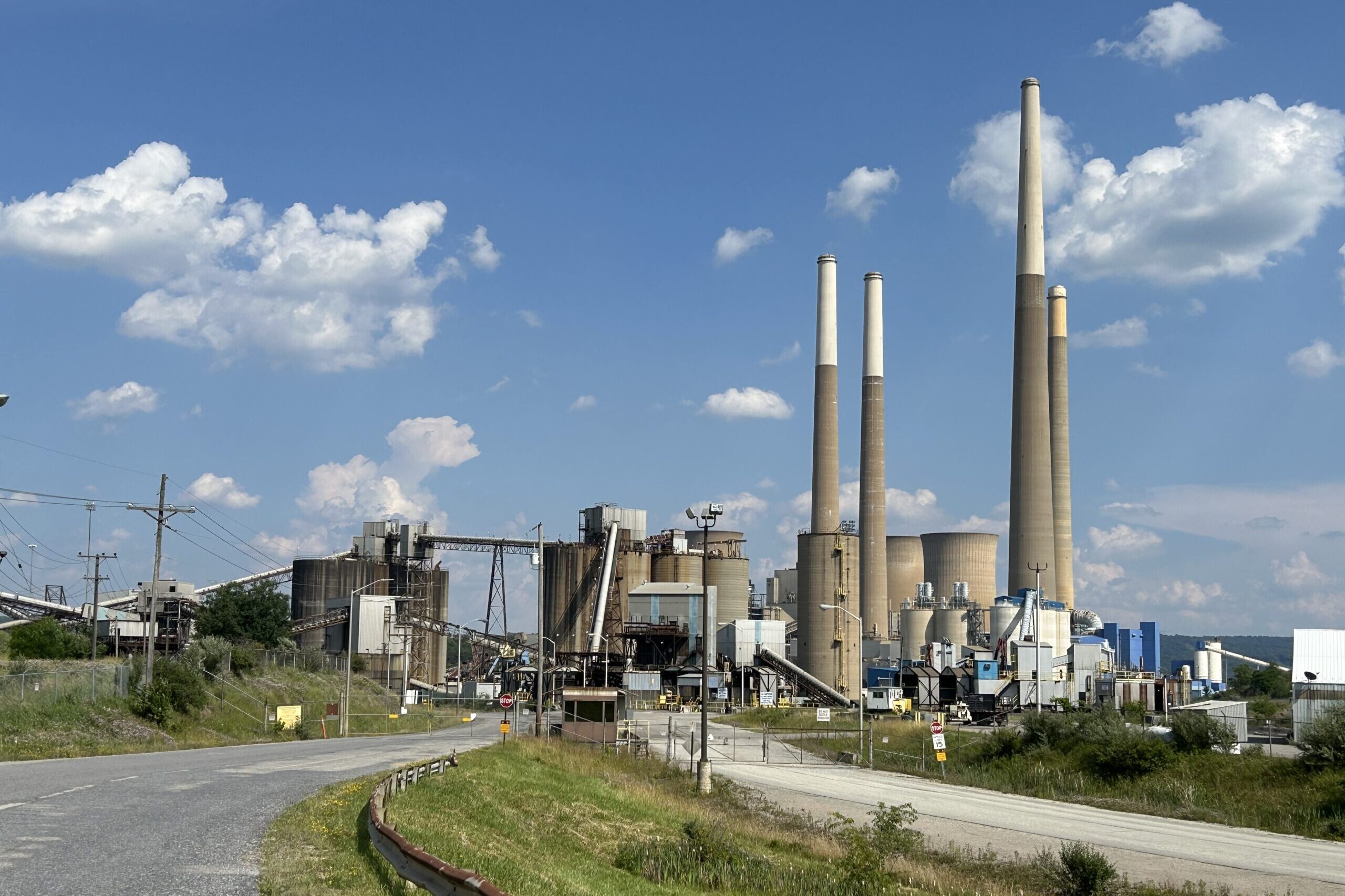 An industrial facility with several large stacks against a blue sky.