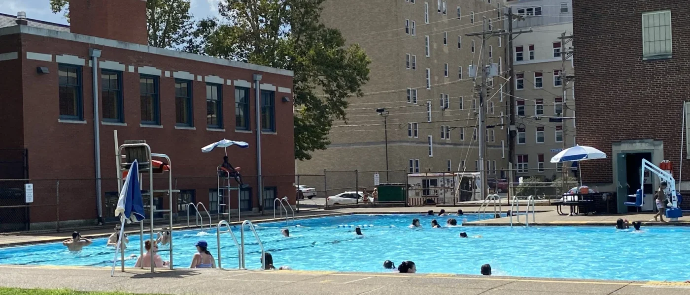 A swimming pool in an urban setting with buildings in the back ground